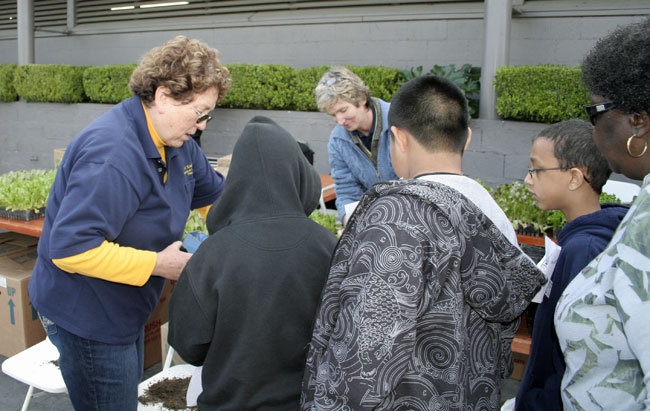 Laura Van Der Staay, left, helps third-graders plant lettuce seedlings.