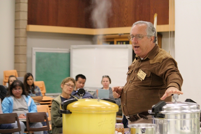 Teacher with pots steaming on stove, and class behind him.