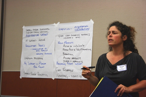 Woman speaking in front of room with hand-written notes behind her.